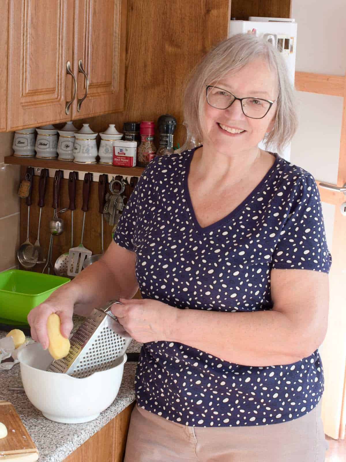 My mom grating potatoes on a hand grater box.