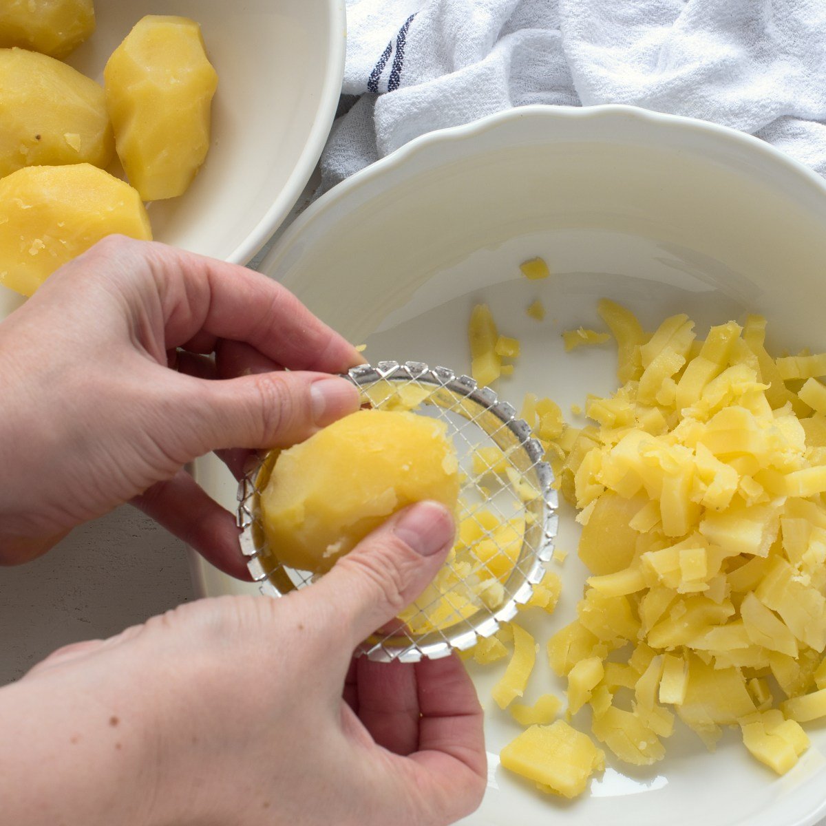 Pressing cooked potato through a potato masher.