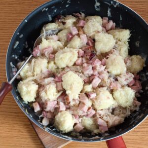 Potato dumplings, sauerkraut and ham served in a pan.