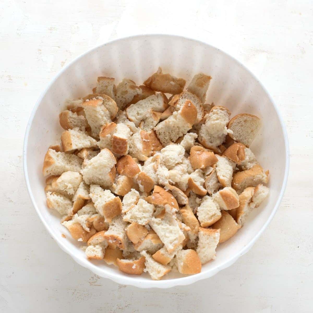 White bread cut into cubes, in a white bowl, soaked in milk.