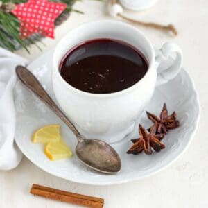 Spiced wine served in a porcelain cup with teaspoon and some spices.