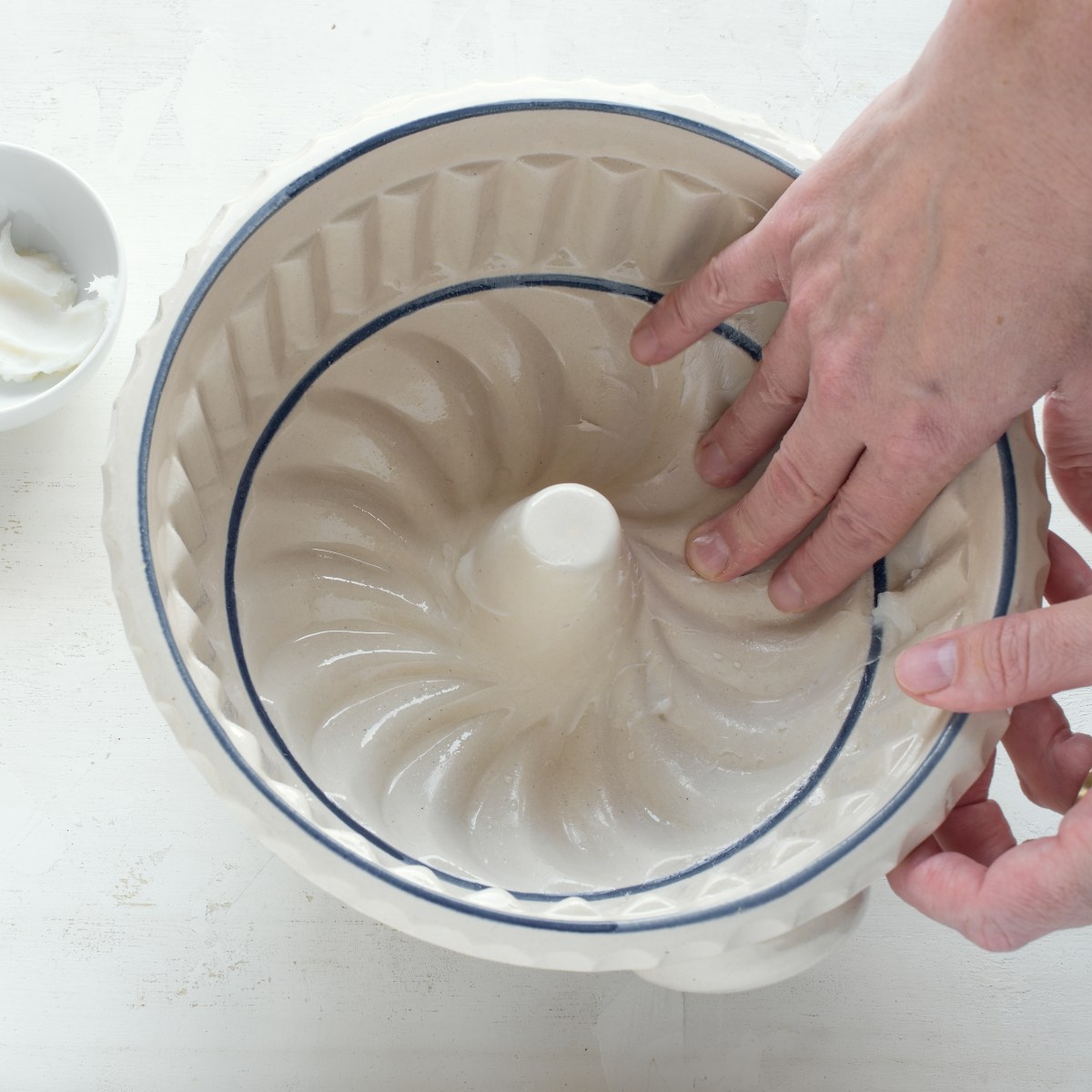 Greasing the inner of a bundt cake pan using fingers.