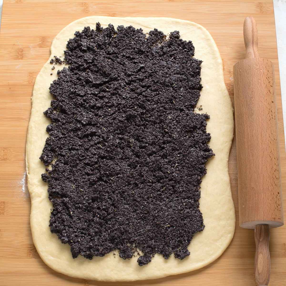 Spreading poppy seed filling over rolled yeast dough.