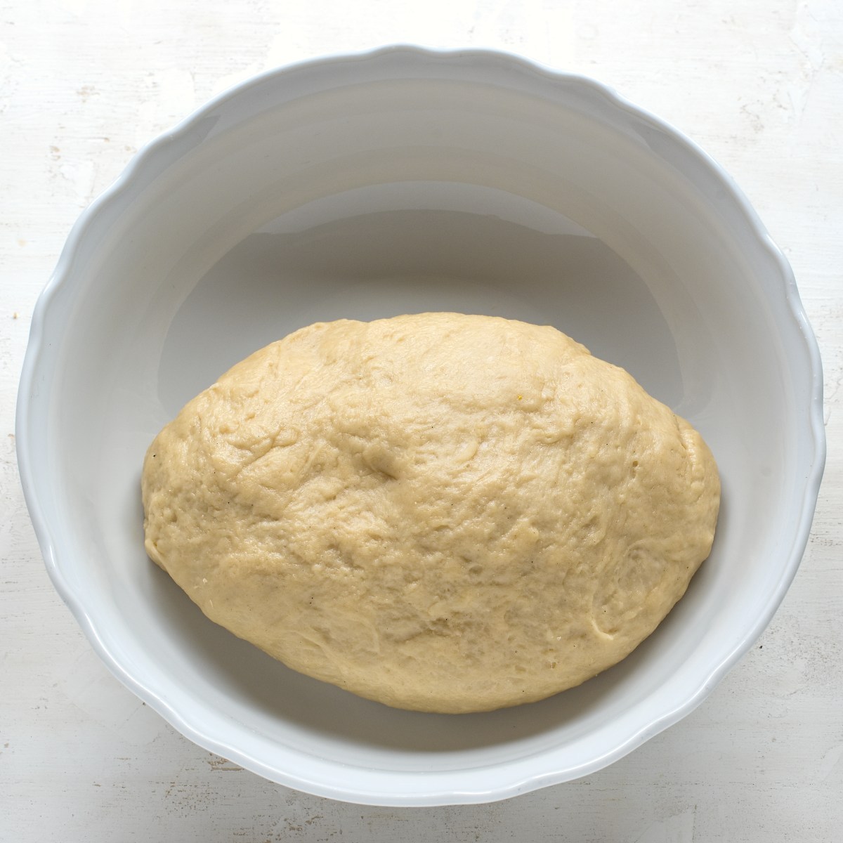 Yeasted dough in a white bowl before letting it to rise.