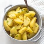 Boiled potatoes with caraway seeds and lovage greens, in a grey bowl.