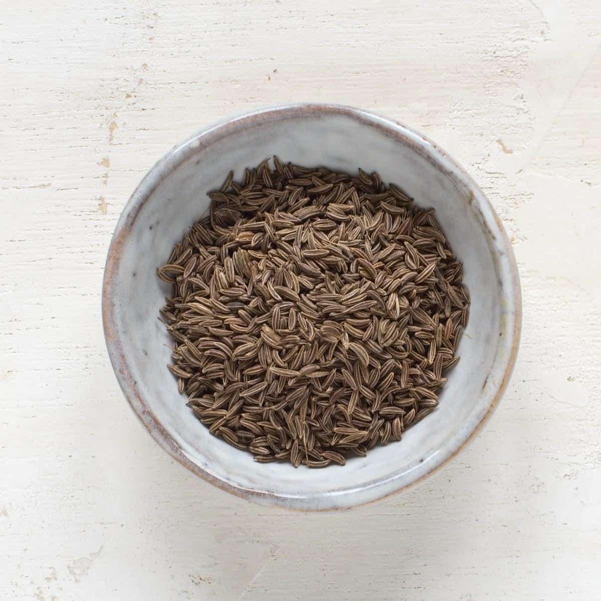 Caraway seeds in a small grey bowl.