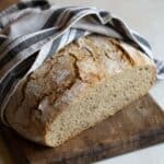 Czech rye bread on a wooden spoon, wrapped in kitchen cloth.