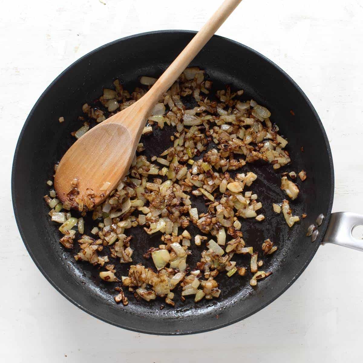 Caramelized onion in a black skillet, with wooden spoon.