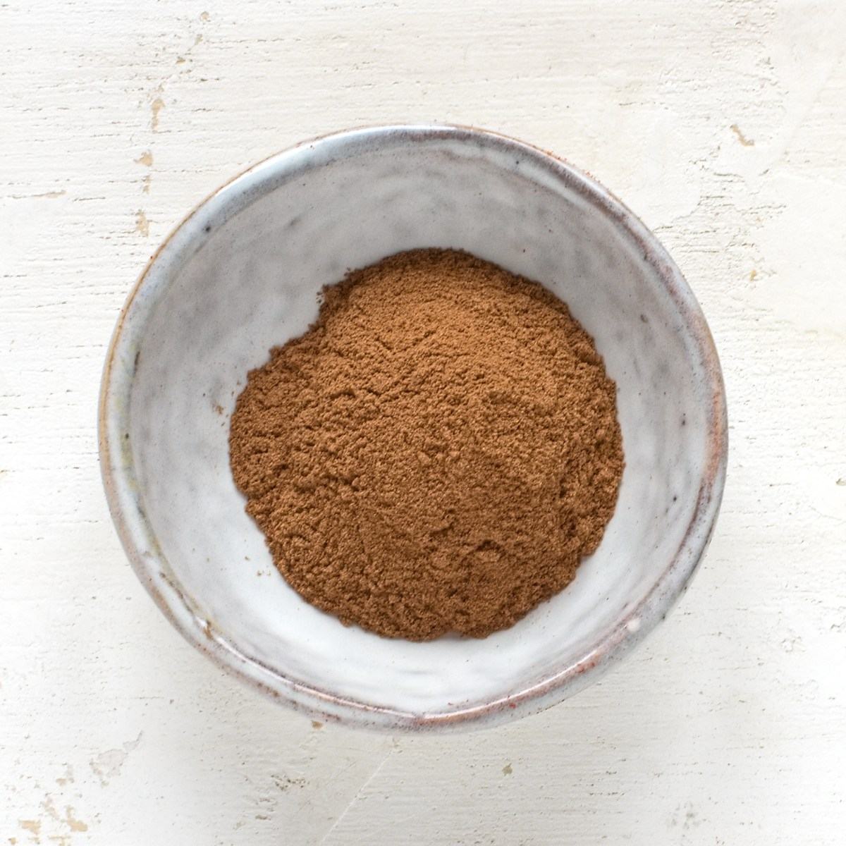 Ground cinnamon in a small grey bowl.