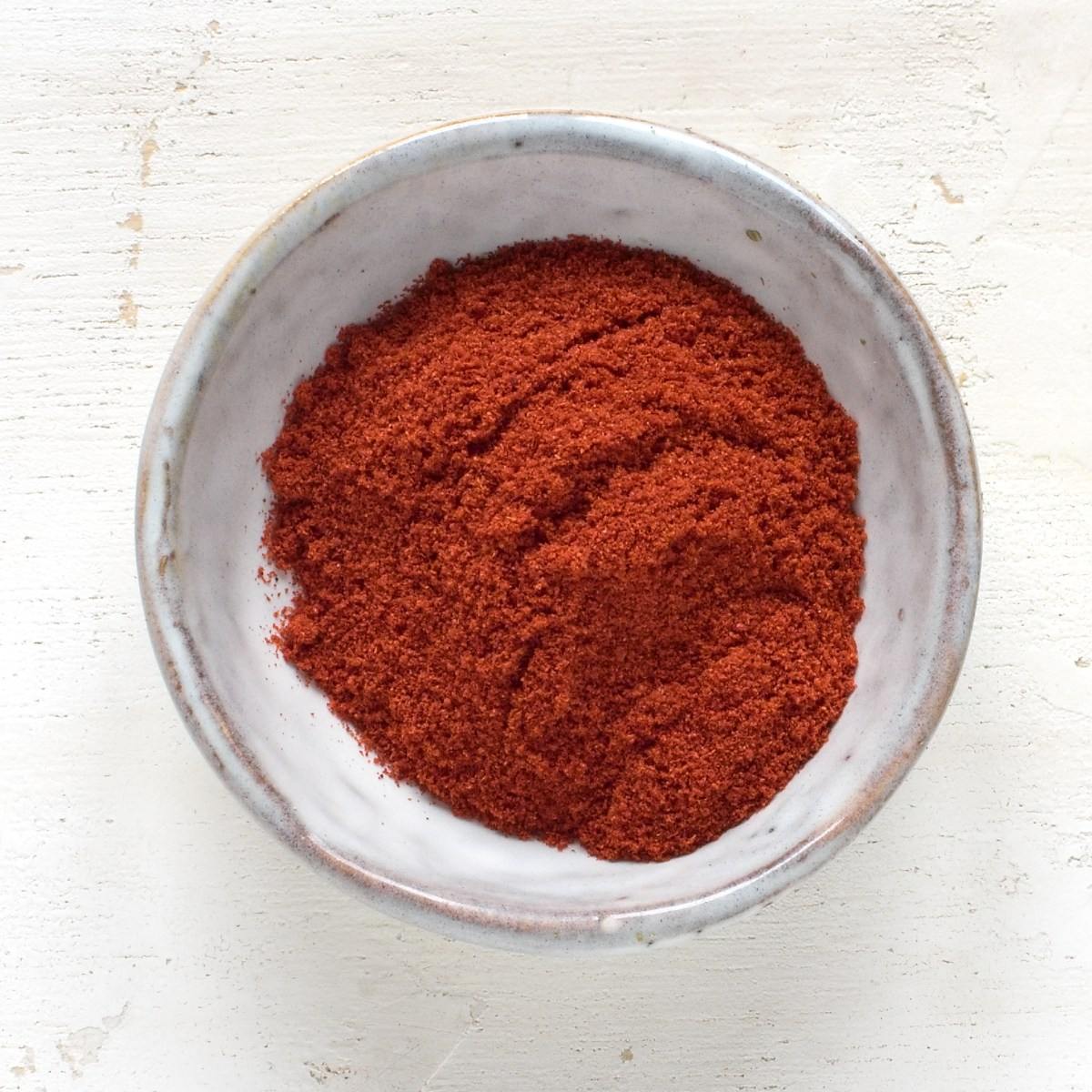 Ground paprika in a small grey bowl.