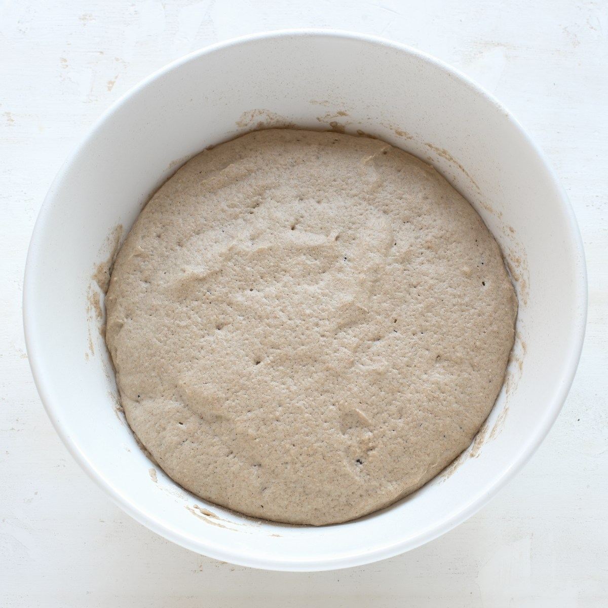 Raised yeast starter for rye bread, in a white bowl.