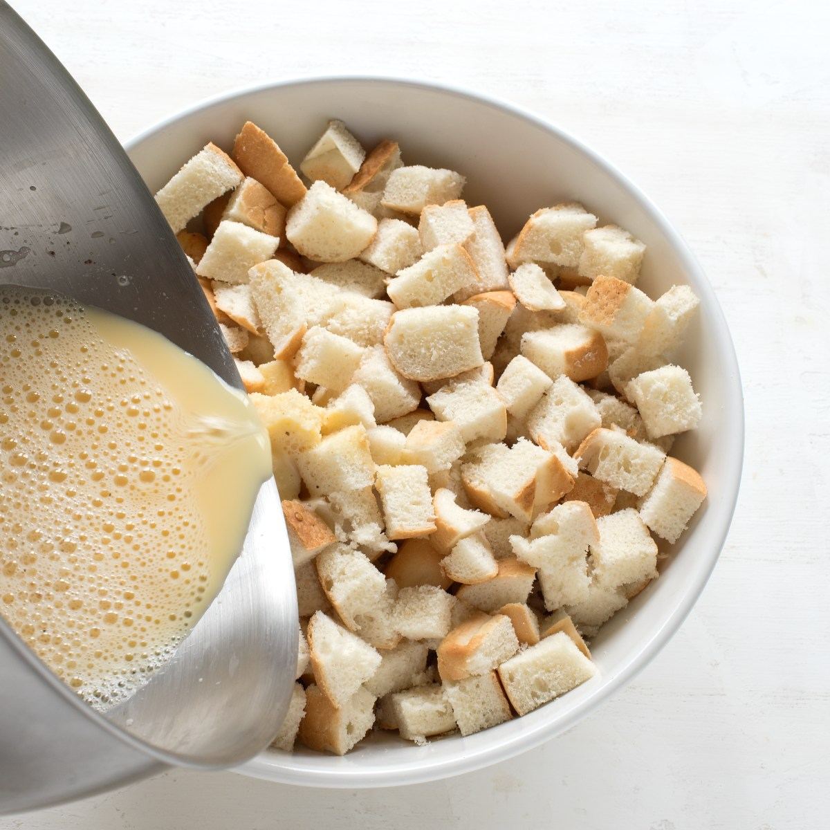 Cubes of white bread in a bowl, poured over with a mixture of egg yolks, milk and seasoning.