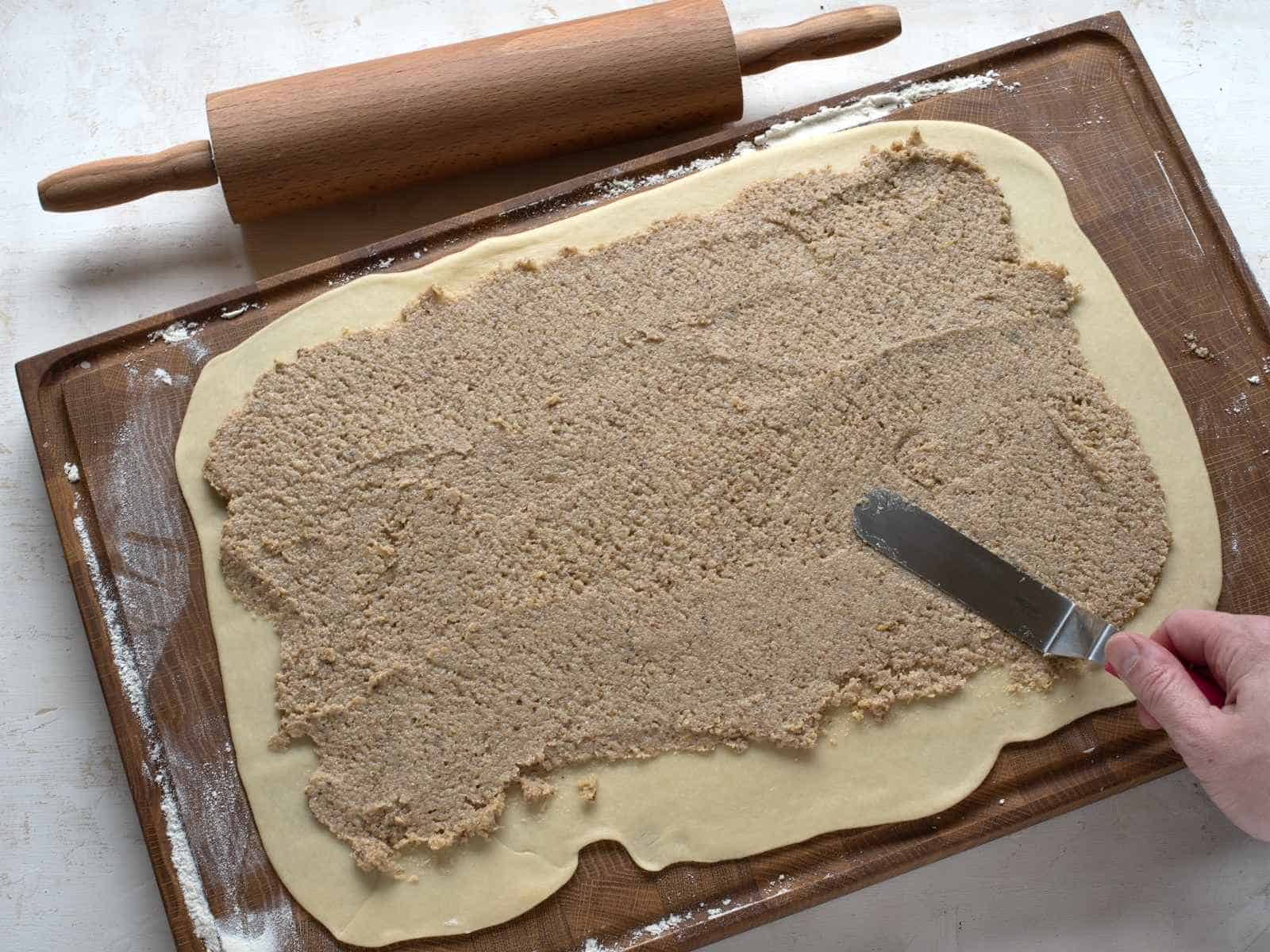 Spreading walnut filling over rolled dough.