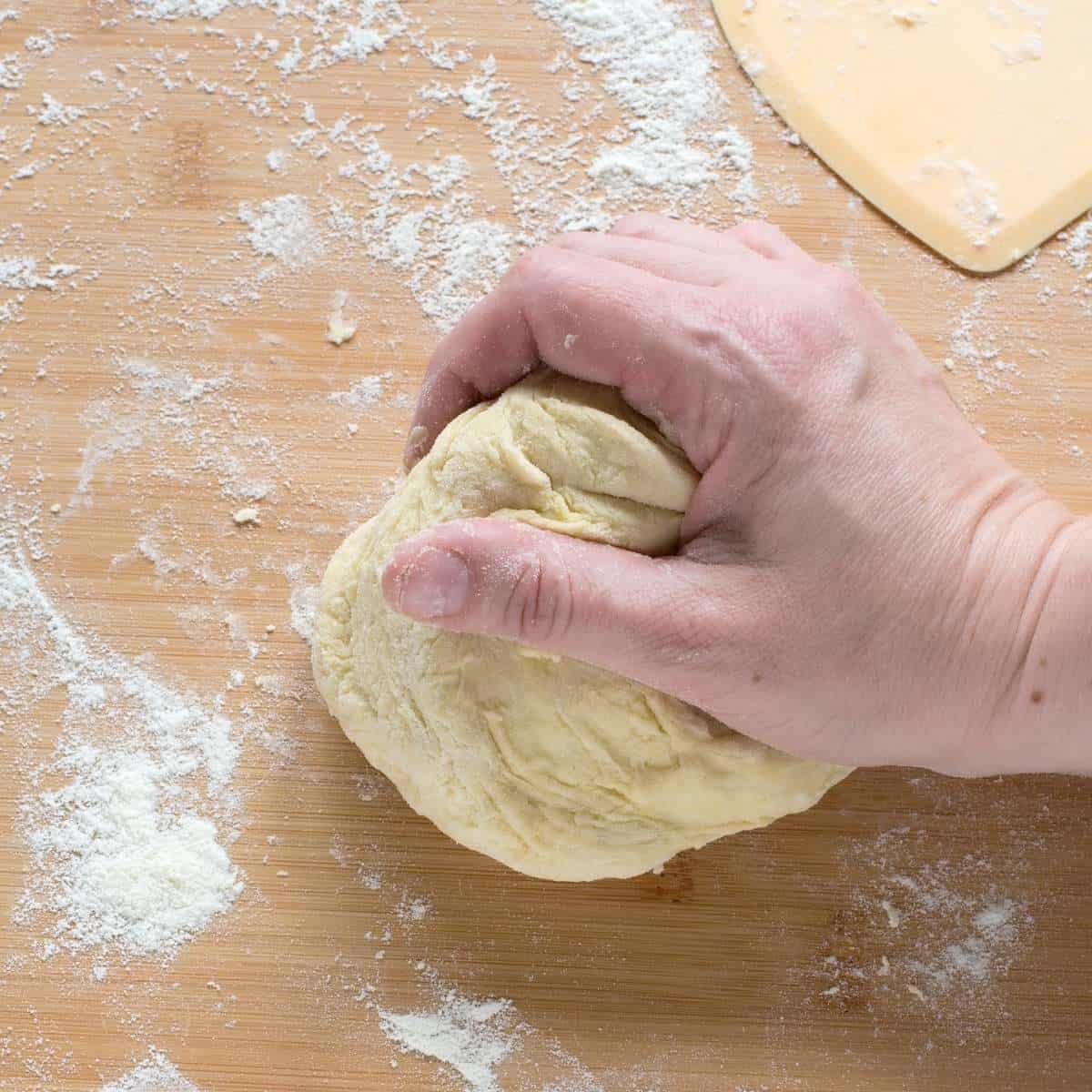 Kneading strudel dough with a hand, on a floured working surface.