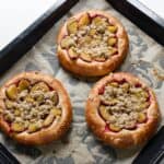 Three Czech plum kolaches on a baking sheet.