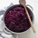 Czech braised sweet and sour red cabbage, in a bowl with a wooden spoon over it.