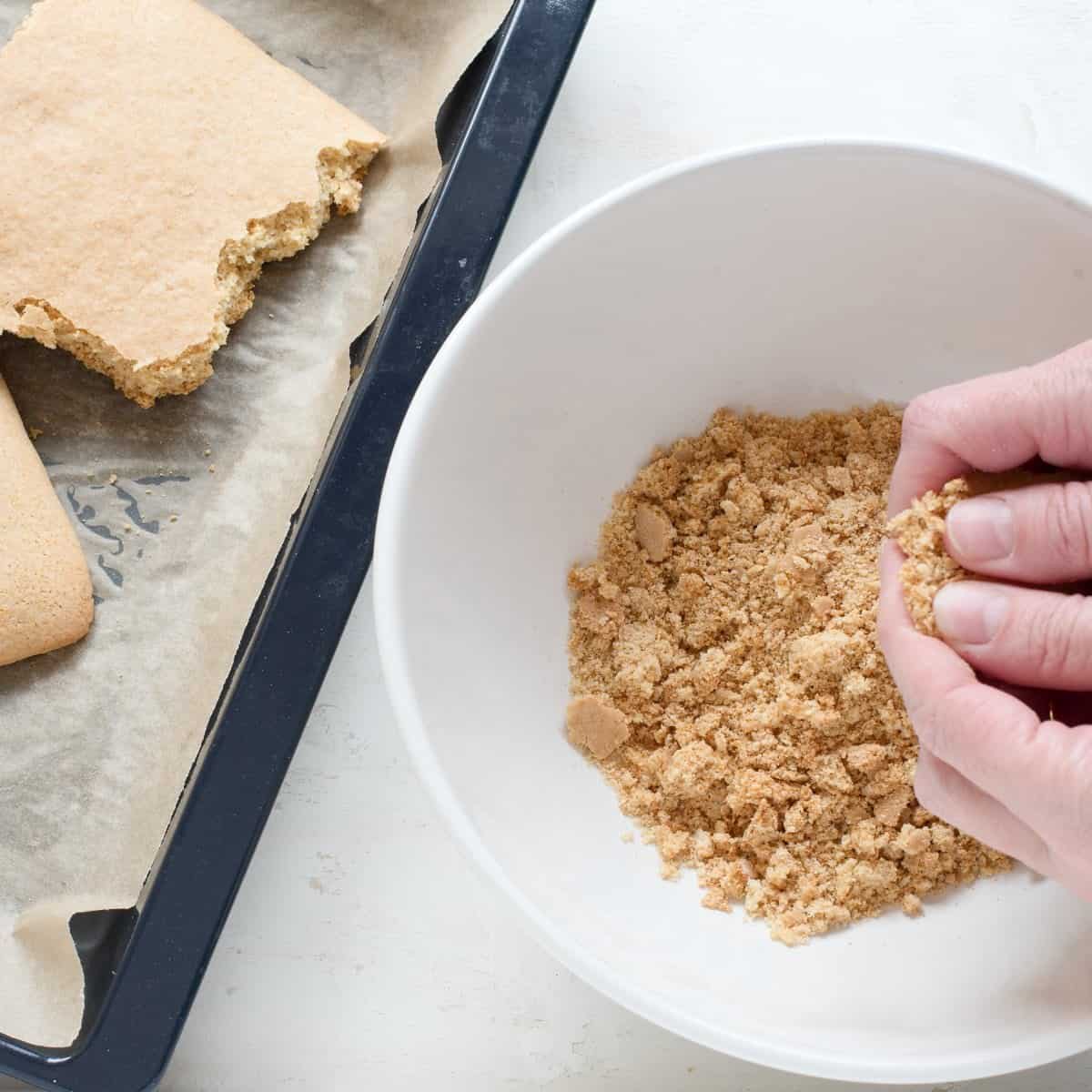 Breaking down the honey dough into crumbs and transferring them into a white bowl using fingers.