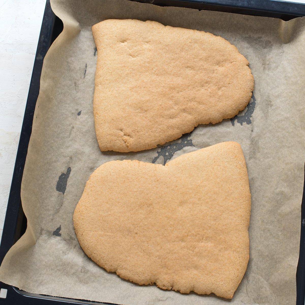 Two sheets of baked honey dough, placed on a a lined baking sheet.