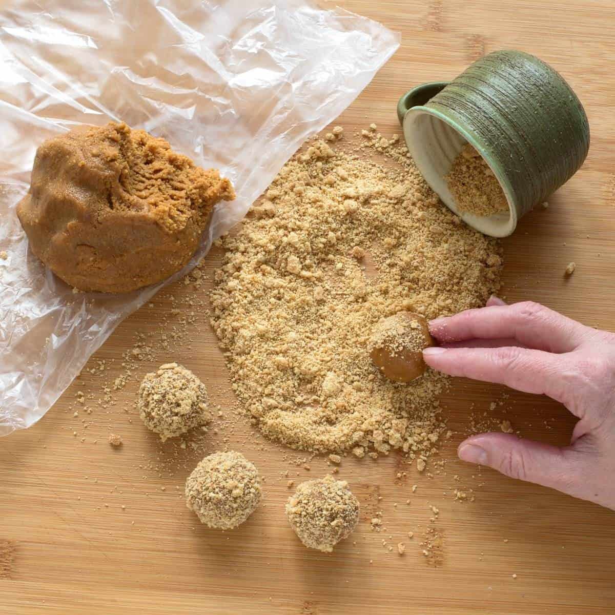 Coating the honey ball cookies with crumbs while a soft honey dough rests on the left.