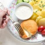 Czech fried Hermelín cheese served with potatoes and tartar sauce. The cheese is cut in half.