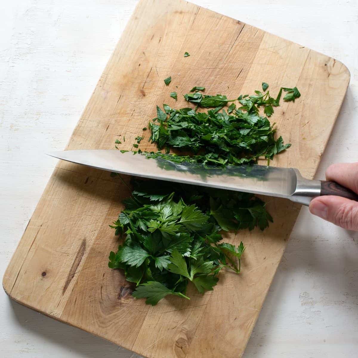 Chopping green parsley on a cutting board.