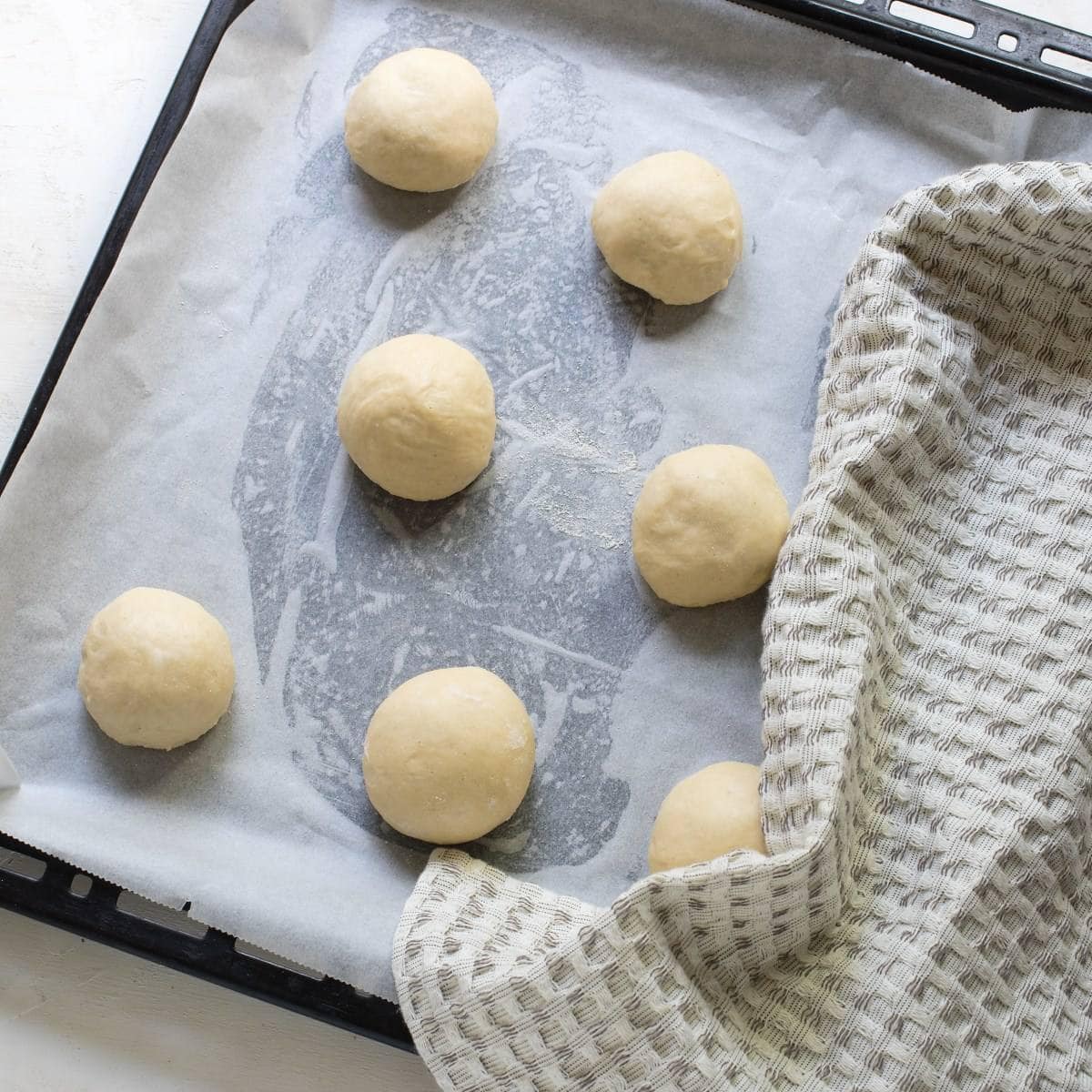 Letting rest the balls of dough on a parchment lined baking sheet.