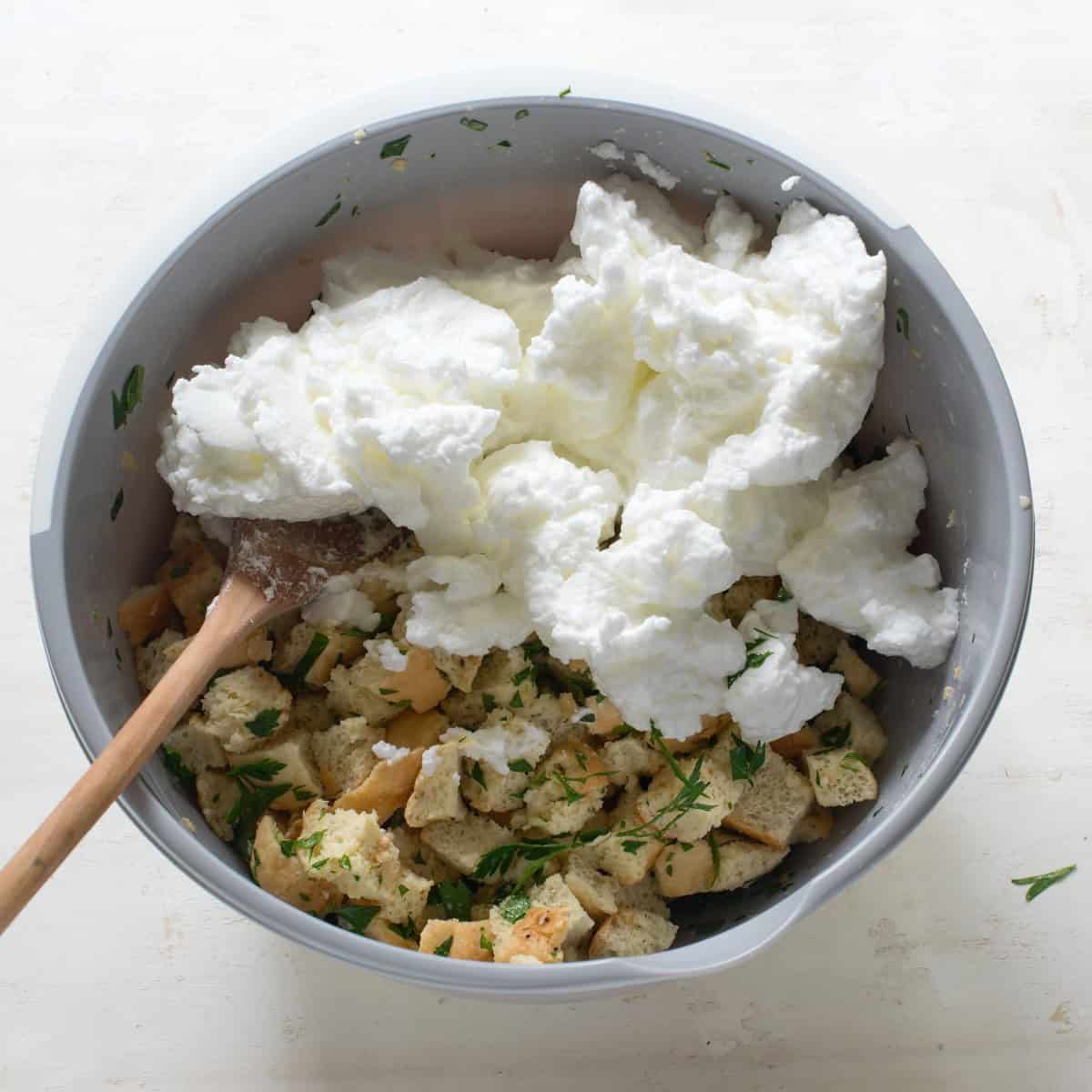 Making the dough for Carlsbad dumplings - bread cubes and stiff-whisked eggs in a gray bowl.