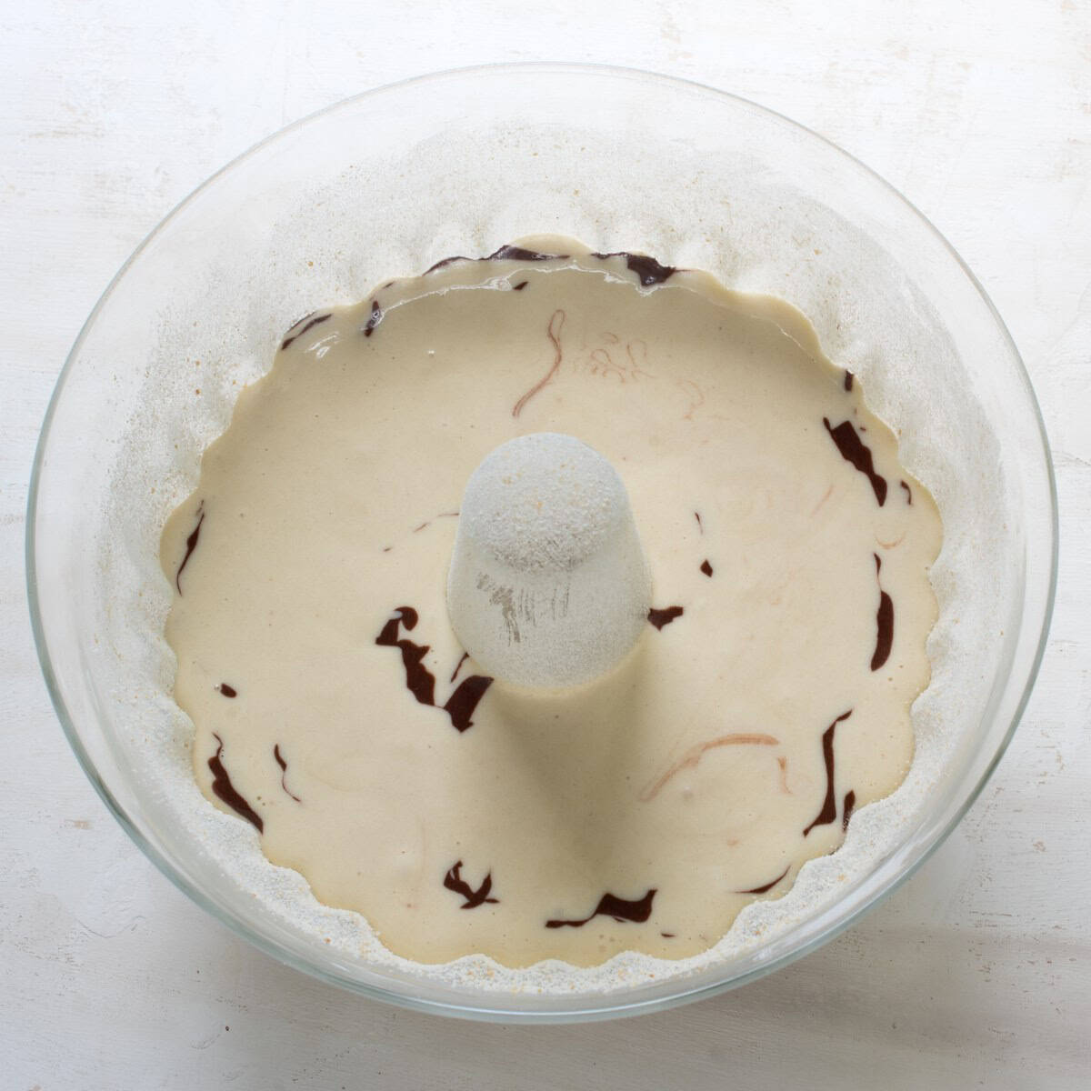 Filling batter into a glass bábovka pan.