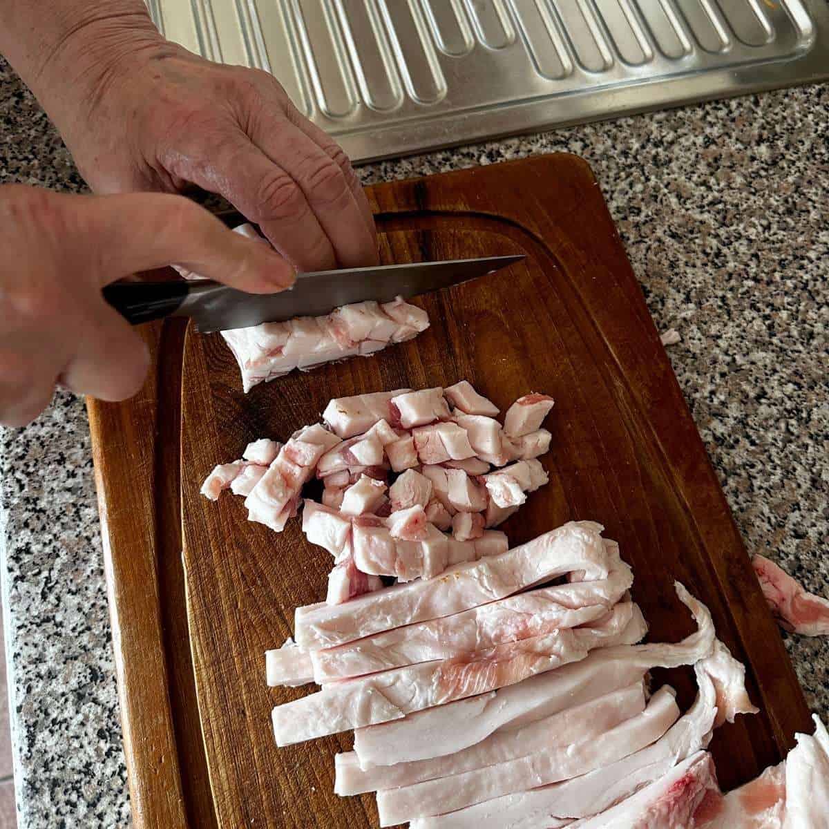 Cutting white pork fat into cubes.