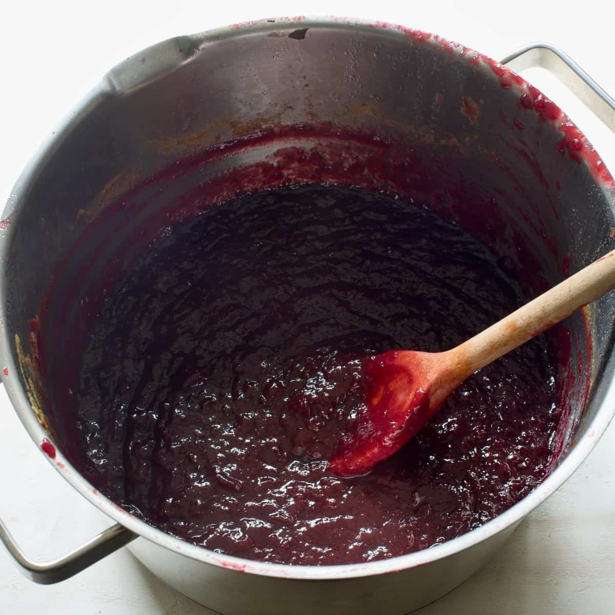 Cooked povidla plum butter, in a pot with a wooden spoon.