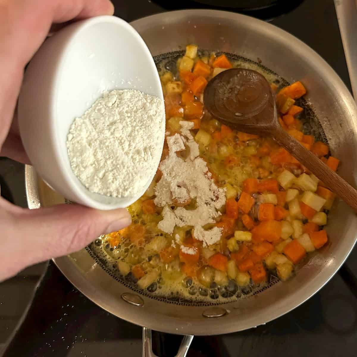 Frying vegetables in a pan, adding flour to make roux.