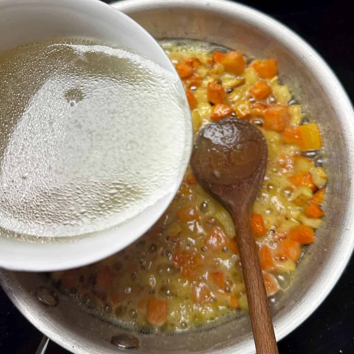 Adding fish broth to frying vegetables.