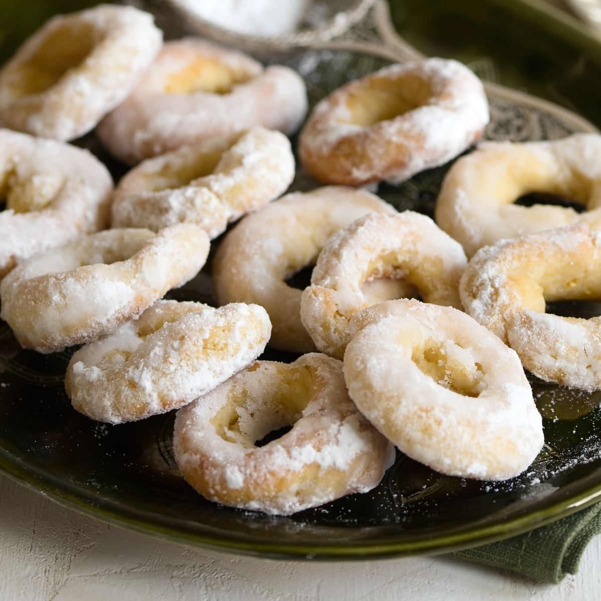 Traditional Czech powdered sugar donuts on a black plate.