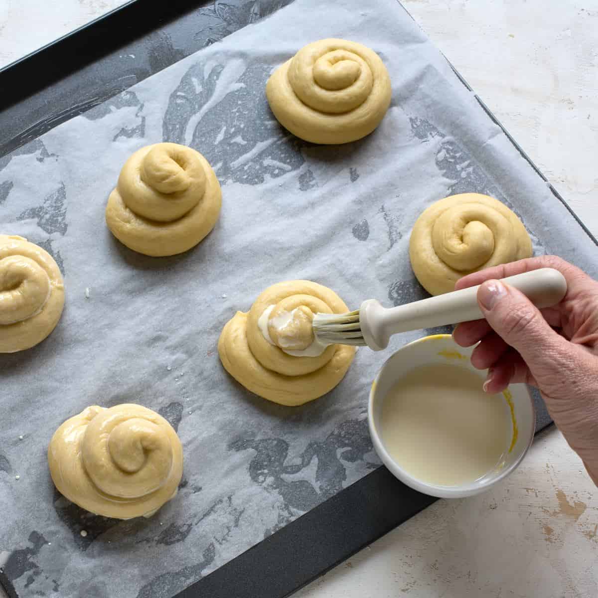 Brushing shaped Jidáše with egg brush before putting them in the oven.