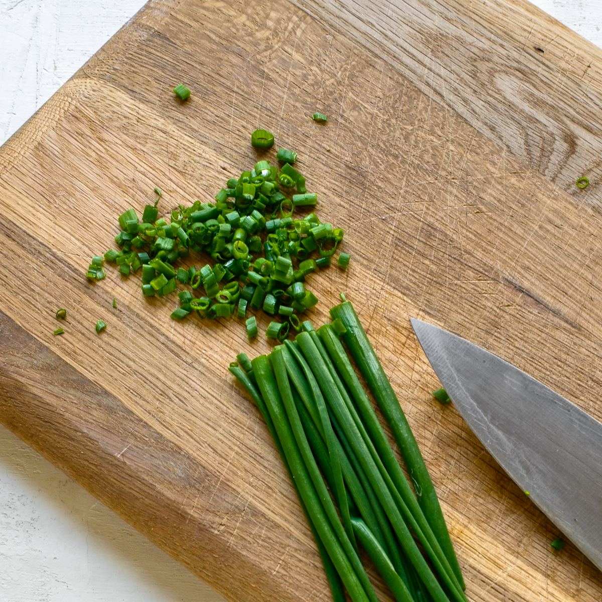 Chopped chives on a wooden bread.