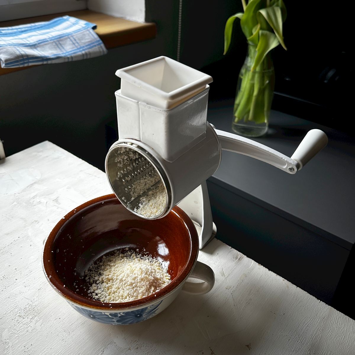 Grinding blanched almonds in a hand rotary grinder.