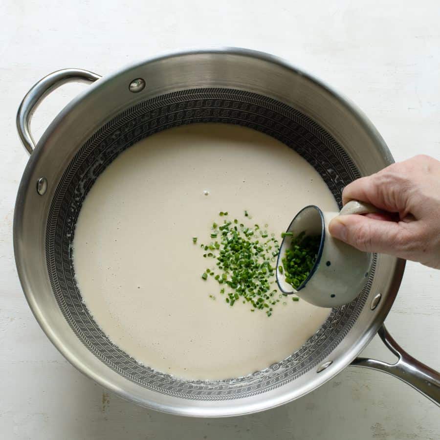 Adding chopped chives to the sauce.