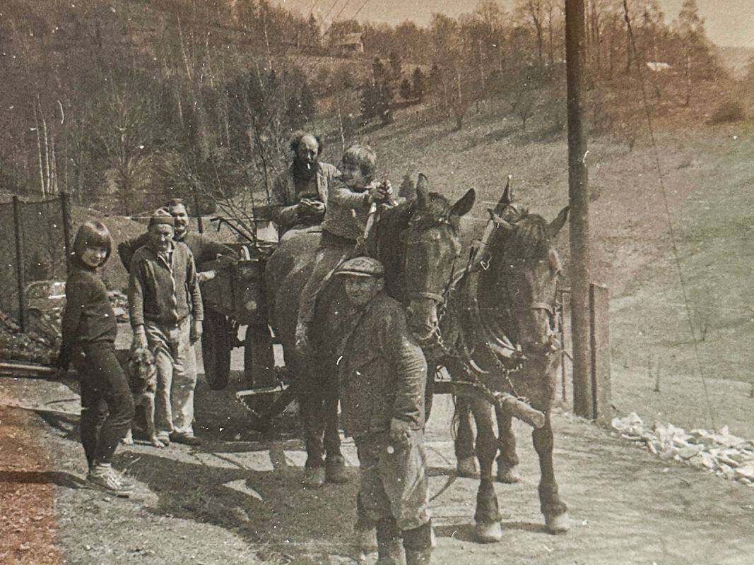 An old photo with horses and people around.
