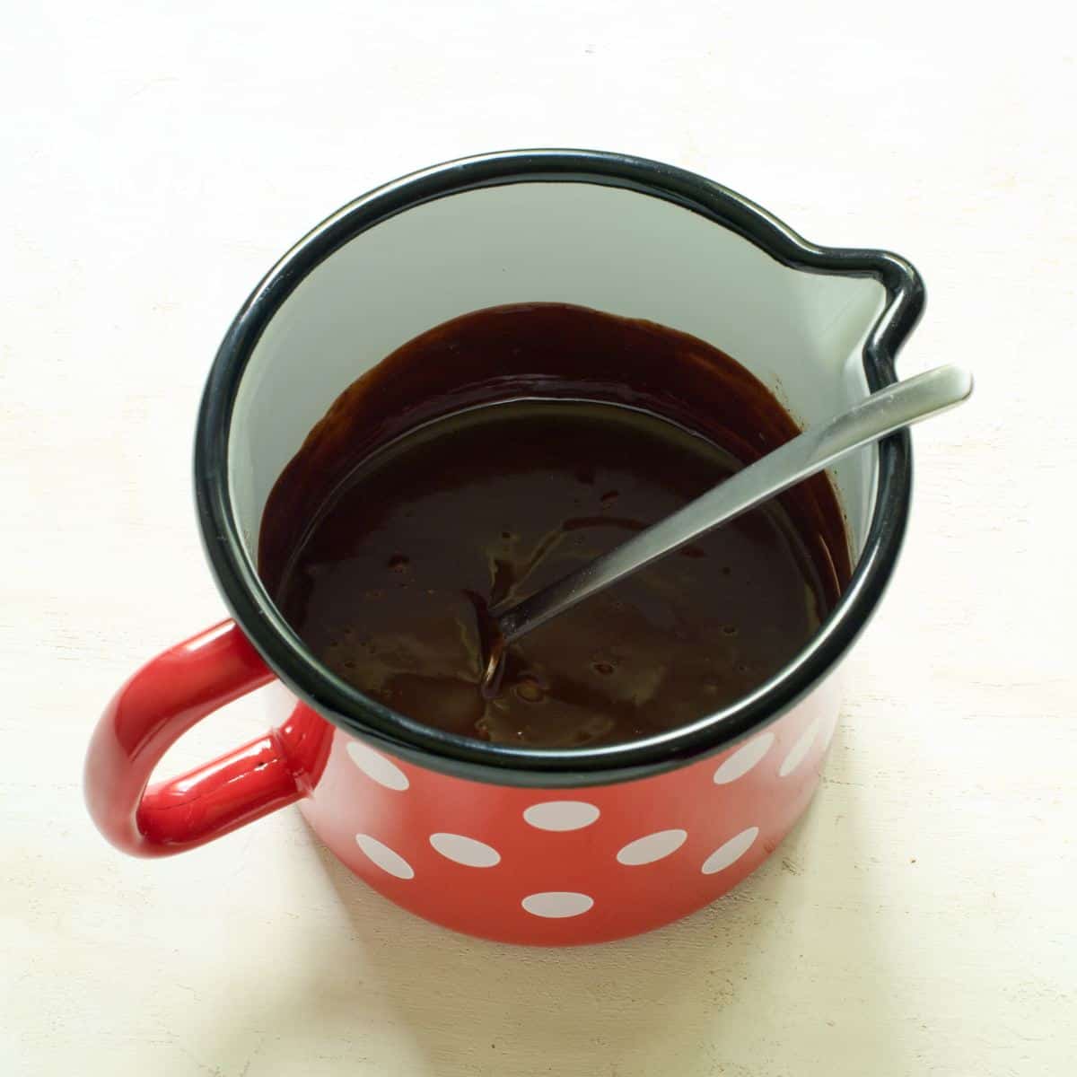 Chocolate ganage in a small dotted saucepan.