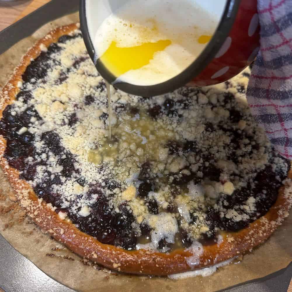 Pouring a mixture of melted butter and rum over baked frgál.
