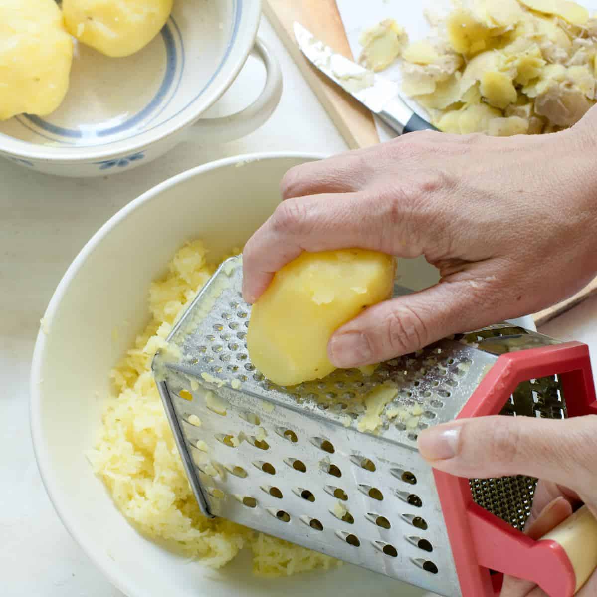 Shredding cooked, peeled potatoes using a hand grater box.