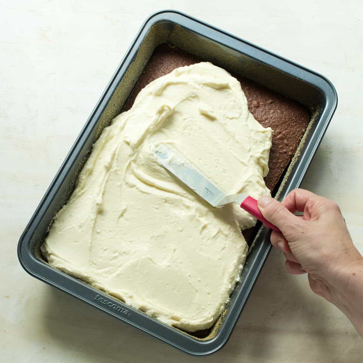 Spreading tvaroh cream over baked cocoa sponge.