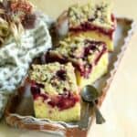 Squares of plum coffee cake with cinnamon streusel topping, arranged on a tray.